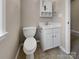 Compact bathroom with a white toilet, vanity, and mirrored cabinet, maximizing space and functionality at 9501 Brighthaven Ln, Charlotte, NC 28214