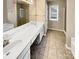 Bright bathroom with a double sink vanity, tile flooring, and a glass-enclosed shower at 9501 Brighthaven Ln, Charlotte, NC 28214