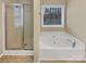 Bathroom featuring a soaking tub, glass-enclosed shower, and window, offering a spa-like experience at 9501 Brighthaven Ln, Charlotte, NC 28214