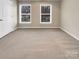 Bedroom featuring neutral-colored carpet, two windows, and a white door at 9501 Brighthaven Ln, Charlotte, NC 28214