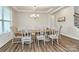Well-lit dining area has luxury vinyl floors and an elegant chandelier above a large wooden table and upholstered chairs at 2408 Napa Ter, Clover, SC 29710