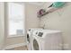 Well-equipped laundry room with modern washer and dryer, a bright window, and overhead storage shelving at 2408 Napa Ter, Clover, SC 29710