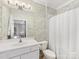 Bright bathroom with a white vanity, patterned wallpaper, and a shower with a curtain at 1121 Park West Dr, Charlotte, NC 28209