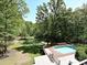 Aerial view of property with pool, large deck, pond, and wooded surroundings at 124 Canterbury Ln, Matthews, NC 28104
