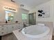 Bright bathroom featuring a large soaking tub, tiled surround, and vanity with mirror at 124 Canterbury Ln, Matthews, NC 28104