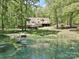 Rear exterior view of home with pond and dock surrounded by lush greenery at 124 Canterbury Ln, Matthews, NC 28104