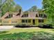 Charming yellow two-story home featuring a welcoming front porch, dormer windows, and attached two car garage at 124 Canterbury Ln, Matthews, NC 28104