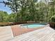 Outdoor in-ground swimming pool with a wood deck surrounded by mature trees at 124 Canterbury Ln, Matthews, NC 28104