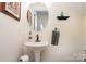 Cozy powder room features a pedestal sink, round mirror, and stylish decor at 125 High Sail Ct, Mooresville, NC 28117