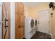 A laundry room with a washer and dryer, a wooden storage cabinet and a white exterior door at 125 High Sail Ct, Mooresville, NC 28117