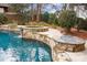 Beautiful pool featuring a stone spa and fire pit, surrounded by lush landscaping in a serene backyard setting at 1312 Lookout Cir, Waxhaw, NC 28173