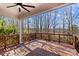 Inviting covered deck with wood railing, ceiling fan, and views of wooded landscape at 137 Hunters Hill Dr, Statesville, NC 28677
