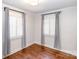 Bright bedroom featuring hardwood floors, white walls, and shuttered windows with gray curtains at 1831 Jameston Dr, Charlotte, NC 28209