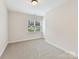 This cozy bedroom offers natural light from the window, plush carpeting, and neutral walls at 2615 Brentwood Pl, Charlotte, NC 28208