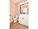 Powder room featuring wood flooring, a white vanity, black hardware, and a matching framed mirror at 2622 Old Camden Rd, Monroe, NC 28110