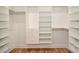 Walk-in closet with custom white shelving, drawers, and hanging rods with wood-look floors at 2622 Old Camden Rd, Monroe, NC 28110