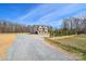 Two story home with gravel driveway, manicured lawn, and wooded backdrop at 2622 Old Camden Rd, Monroe, NC 28110
