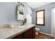 Cozy bathroom featuring a single sink vanity, a framed mirror, light blue walls, and a window with blinds at 360 Patience Dr, Concord, NC 28025