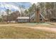 Charming two-story home with a brick chimney, metal roof, and gray siding, surrounded by lush greenery and mature trees at 360 Patience Dr, Concord, NC 28025