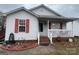 Charming home with a brick foundation and front porch, and a cozy entrance with a storm door and red shutters at 376 Brookgreen Nw Pl, Concord, NC 28027
