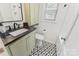 Bathroom vanity with black countertop, white cabinets, shower, and patterned tile floor at 4635 General Pershing Dr, Charlotte, NC 28209