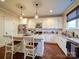 Bright kitchen with a central island, white cabinetry, stainless steel appliances, and hardwood flooring at 508 Summerfield Pl, Belmont, NC 28012