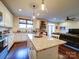 Open kitchen showcasing a large island, hardwood floors, stainless appliances, and seamless flow to living area at 508 Summerfield Pl, Belmont, NC 28012
