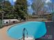 Inviting pool area with a dark wood deck, outdoor seating, and lush landscaping at 6319 Hazelton Dr, Charlotte, NC 28210