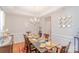 Formal dining room featuring a chandelier, glass-top table, and wainscoting, ideal for elegant dining experiences at 10406 Little Whiteoak Rd, Charlotte, NC 28215