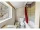 Small bathroom with white toilet and a tub, bathed in natural light from the window at 1216 E Cedar Ave, Gastonia, NC 28054