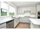 Well-lit kitchen showcasing gray cabinets, modern appliances, a window over the sink, and hardwood flooring at 1270 Brawley School Rd # E, Mooresville, NC 28177