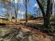 Sloping yard with mature trees, providing shade, and a convenient carport in the distance at 1377 S Aspen St, Lincolnton, NC 28092