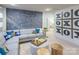Cozy living room with a plush sofa, tufted ottoman, unique wall decor, and a connecting doorway at 13935 Penbury Ln # 378, Charlotte, NC 28278