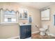 Traditional bathroom with a blue vanity, toilet, built-in storage, and a shower with floral curtain at 1911 Woodlawn St, Kannapolis, NC 28083