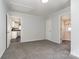 This bedroom has gray walls, gray carpet, and two doorways, one leading to the kitchen at 1911 Woodlawn St, Kannapolis, NC 28083