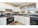 Well-lit kitchen featuring white cabinets, stainless steel appliances, and a double sink overlooking outdoors at 1911 Woodlawn St, Kannapolis, NC 28083