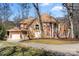 Stunning two-story home featuring a combination of stone and wood facade, mature trees, and a spacious driveway at 20338 Christofle Dr, Cornelius, NC 28031