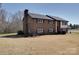 View of the side and front of a brick home, with a spacious lawn and mature trees at 257 Hickory Hill Ln, Stanley, NC 28164