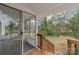 View from a wooden back porch into a screened in room with white wicker furniture at 3504 Meredith Ave, Charlotte, NC 28208