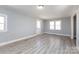 Spacious living room with gray walls, wood-look flooring, and ample natural light from multiple windows at 4211 Little Mountain Rd, Gastonia, NC 28056