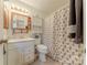 Well-lit bathroom with vanity, toilet, cabinet, and shower featuring a floral patterned shower curtain at 4840 Autumn Leaf Ln, Charlotte, NC 28277