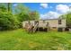 View of the home's expansive backyard with a wooden deck, green lawn, and mature trees at 5128 Green Leaf Ct, Mount Holly, NC 28120