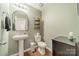 Stylish half bathroom with a pedestal sink, decorative shelves, and modern fixtures for added convenience at 5306 Graypark Dr, Charlotte, NC 28269