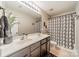 Modern bathroom featuring a double sink vanity, decorative mirror, and a shower with leaf-patterned curtain at 5306 Graypark Dr, Charlotte, NC 28269