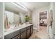 Well-lit bathroom with a double sink vanity, large mirror, and an adjacent walk-in closet for ample storage at 5306 Graypark Dr, Charlotte, NC 28269