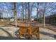 Spacious backyard featuring a gravel patio with a wooden table and chairs surrounded by mature trees at 6215 Coatbridge Ln, Charlotte, NC 28212