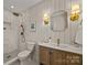 Bathroom featuring a shower, vanity, light fixtures, toilet, mirror and wainscoting at 6215 Coatbridge Ln, Charlotte, NC 28212