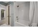 Bathroom with a combined shower and tub, white subway tiles, and gold fixtures at 6215 Coatbridge Ln, Charlotte, NC 28212