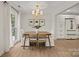 Bright dining room with a natural wood table, white upholstered chairs, and modern lighting at 6215 Coatbridge Ln, Charlotte, NC 28212