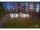 Beautiful home at dusk featuring a well-manicured lawn and mature trees at 6215 Coatbridge Ln, Charlotte, NC 28212